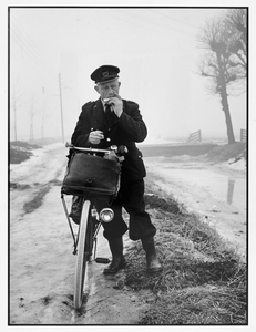 301214 Afbeelding van een postbode die een shaggie rolt op de Scheendijk te Breukelen, tijdens de winter van 1963.